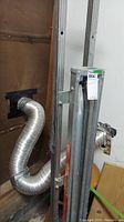 Metal equipment stabilizer leaning against wall with vent pipes nearby in garage setting