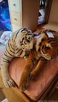 Photo showing both stuffed tigers on a bed, one white tiger with black stripes and one traditional orange tiger with black stripes