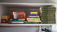 Shelf with Charles Dickens Complete Works hardcover books green with gold, cookbooks, recipe cards in plastic box, and other assorted books