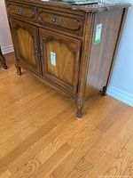 Side and front view of wooden buffet cabinet showing drawers, doors, and carved decorative panels.
