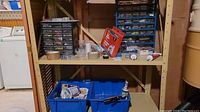 Beige plastic shelving unit with multiple blue bins and clear plastic organizers arranged with assorted hardware and tool items.
