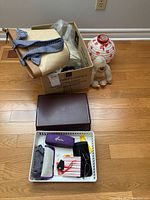 Box with clutches and purses, brown clutch purse outside box, tray containing glasses, cases, and accessories.