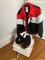 Photo showing the vintage Ottawa Rough Riders jacket hanging on wall, foam game helmet with R logo, and stacked white bleacher cushions.