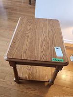 Top-down angled view showing wooden top with natural wood grain and table legs with lower shelf.