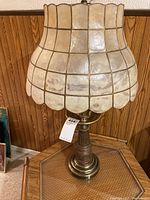 Full view of the vintage table lamp showing metal base and capiz shell lampshade with grid pattern and scalloped edges.