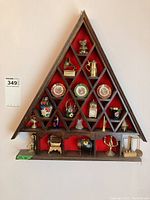 Overview photo of the wooden triangular display shelf mounted on wall with multiple miniature decorative items inside compartments