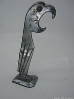 Front side view of the vintage art deco eagle-shaped metal bottle opener showing curved hook and engraved feather details.