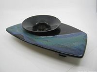 View of the asymmetrical ceramic vase with attached round flower frog, showing glaze colors and shape.