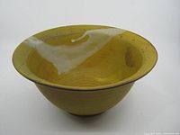 Yellow handmade ceramic bowl with a flared rim and visible circular wheel markings, shown from above and front angle.