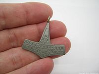 Front view of the Jorgen Jensen Thor's Hammer pendant showing detailed circular patterning and overall shape, held in hand for size reference.