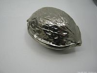 Top-side view of large chrome metal nutcracker shaped like a walnut showing textured surface and metal finish.