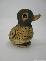 Front-right angled view showing the bird's face, body shape, and painted surface texture with polka dot pattern and glossy eyes.