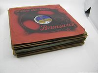 Stack of vintage 78rpm records in original sleeves, showing wear and damage on some sleeves, with Brunswick label visible on top record.