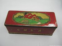 Top view of the old C.W.S. biscuit tin showing countryside cottage illustration on the lid with some paint wear.