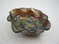 Top angle view of the iridescent carnival glass bowl showing the ruffled edges and embossed cherry and leaf pattern.