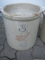 Front view of the beige ceramic crock with number '3' and wing design, showing overall condition and size.