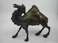 Front and side view of vintage solid bronze camel sculpture showing detailed fur texture and pose.