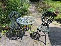 Wide shot showing round table and two chairs on driveway with garden background