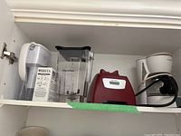 Shelf with Blendtec blender base and jar, Brita water pitcher with filter box, and Mr. Coffee coffee maker