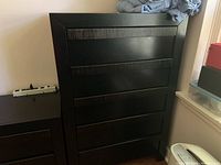 Front full view of the dark wooden chest of drawers showing four horizontal drawers with textured wooden pulls.