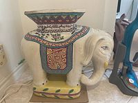 Front and side view of the hand-painted ceramic elephant plant stand showing detailed patterns and posture.