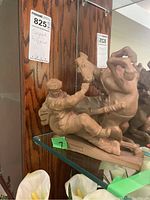 Front view of tan statue showing rearing horse, rider and cart on glass shelf