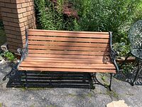 Front view of the bench showing wooden slat seat and back with cast iron frame