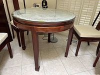 Full front view of round rosewood table with glass top and doily