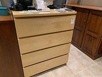 Front and left angle view of the dresser showing light wood drawer fronts and top with darker wood sides.