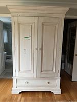 Front view of painted white Ethan Allen cabinet with two doors and bottom drawer closed.