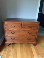Front view of the wooden dresser showing four drawers and metal handles.