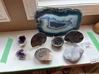 Overview of lot items: agate slab, amethyst geode halves, geode bowl and two ammonite fossils