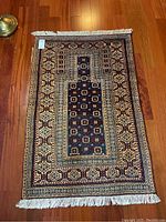 Full view of prayer rug showing overall geometric and floral pattern with vibrant colors and cotton fringe.