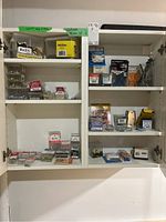 Full view of cabinet unit filled with assorted hardware items such as nails, screws, packages of fasteners and hooks.