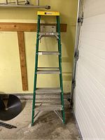 Front view of Davidson fiberglass step ladder showing yellow top, green frame, and metal steps.