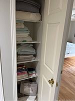 Closet view showing shelves stacked with various linens including sheets, towels and packaged heated blanket