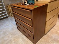 Side and front view of mid century modern wood dresser with five drawers and integrated wooden handles.