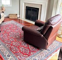 Living room view showing red Persian rug under leather recliner in front of fireplace