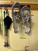 Snowshoes and poles hanging on wall hooks, clear view of snowshoes and part of poles and bike seat