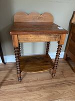 Front view of wood washstand showing twisted legs, scalloped backboard, and lower shelf.