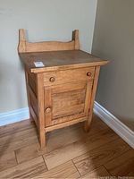 Front and side view of the wooden washstand showing the drawer and cabinet door with knobs and backboard.