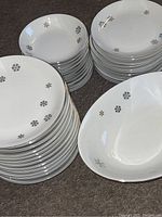 Stacked white plates with silver starflake/snowflake designs and silver rims, along with bowls and a large serving dish visible.
