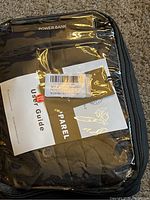 Photo shows Sailwind heated vest packed inside a clear plastic case along with a camouflage power bank and user guide.