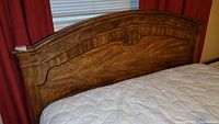 Full view of the wooden headboard showing decorative grain, carving and crest design.
