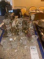 Crystal and brass candle holders with a crystal bird-themed dinner bell arranged on countertop.