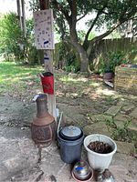 Overview of all items including chimenea fire pit, planters, thermometer, wind chimes, and torch balls on outdoor patio.