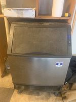 Front view of stainless steel ice machine with black top lid and control panel