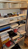 Wide view of multiple wooden shelves filled with various office supplies and storage boxes showing the quantity and arrangement of items.