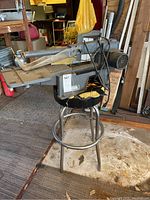 Full view of Craftsman table saw mounted on metal stool, showing saw blade slot, motor housing, power cord, and blade guard within a garage setting.