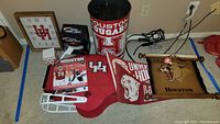 Wide view of the lot showing UH trash can, pennants, framed cougar banner, football helmet, booklet, and light projector box